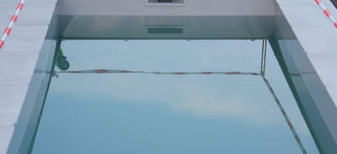 Nahaufnahme: Beckenkante mit umlaufender Plattenreihe und Wasserlinie