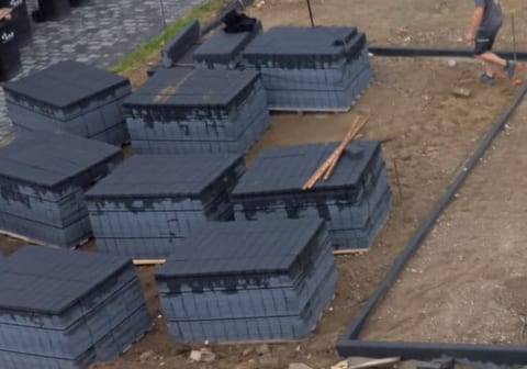 Nahaufnahme: gestapelte Rigolenblöcke fuer die Regenwasserversickerung auf der Baustelle