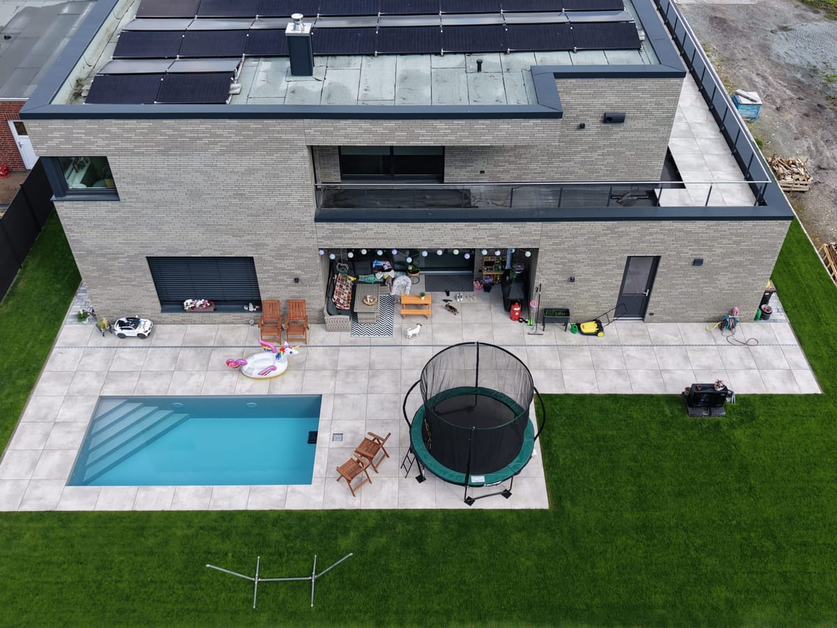 Steile Luftaufnahme derselben Anlage: Terrassenflaeche, Becken und Rasenkante im Verhaeltnis zum Baukoerper