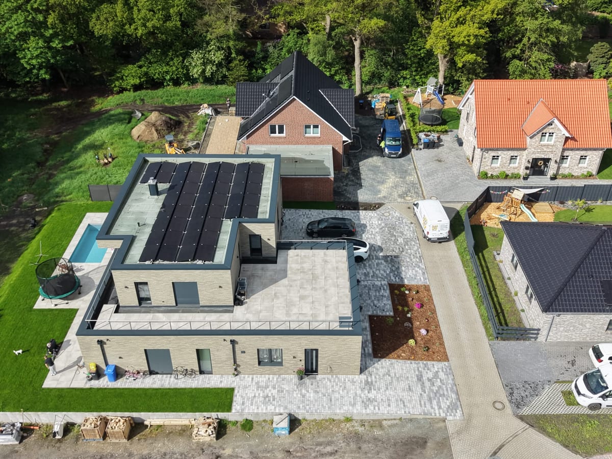 Luftaufnahme eines fertigen Grundstuecks mit Pflasterflaechen, Zufahrt, Pool und Beeteinfassung
