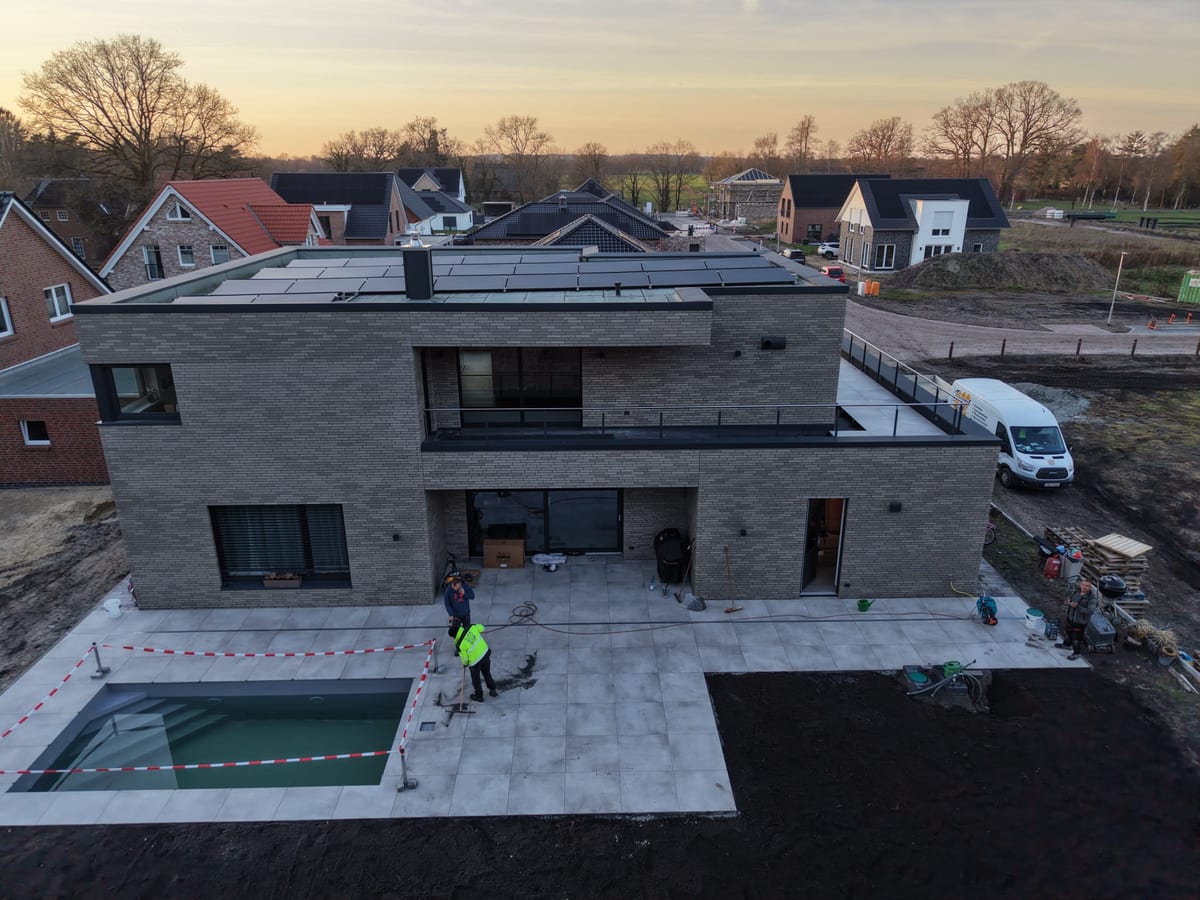 Luftaufnahme in der Daemmerung: Wohnhaus mit fertiger Terrasse, Schwimmbecken und Firmentransporter