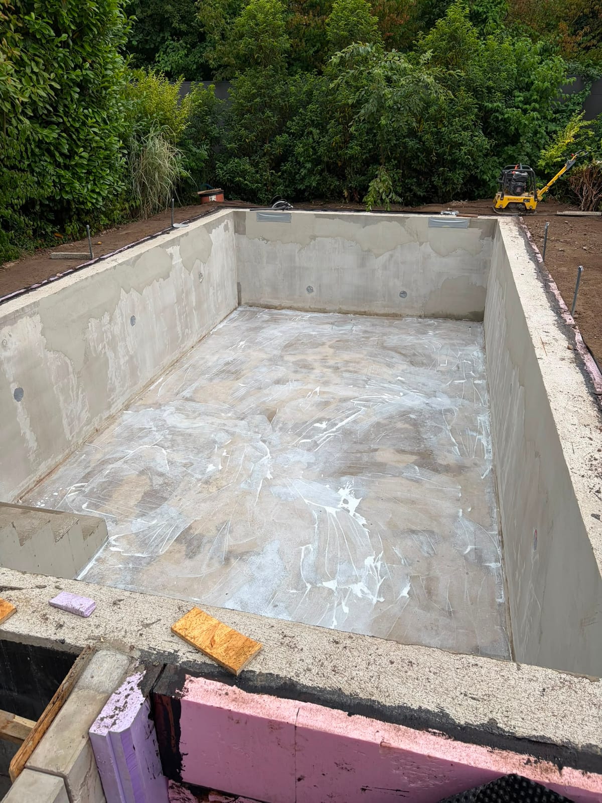 Rohbau eines Schwimmbeckens aus Beton mit verputzten Waenden und eingebauten Einstroemduesen