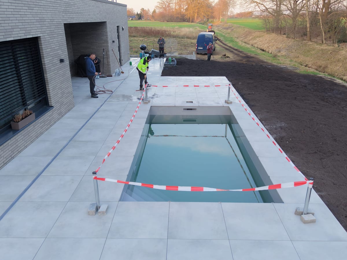 Gefuelltes Schwimmbecken mit umlaufender Terrasse aus grossformatigen Betonplatten